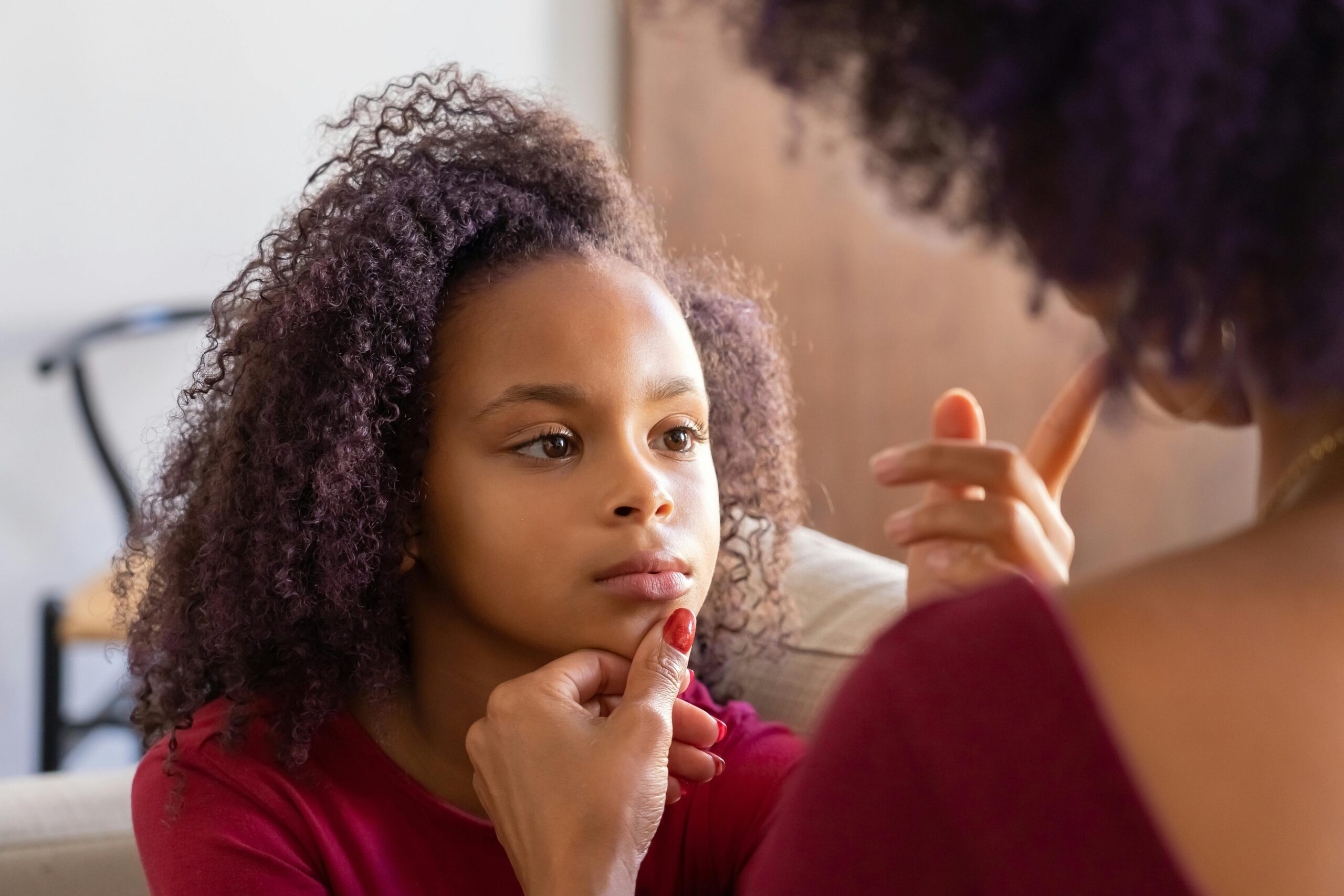 A tender moment between mother and daughter indoors. Focus on love and connection.